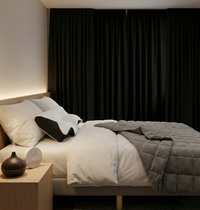 Chambre préparée pour le repos avec rideaux occultants fermés, oreiller ergonomique, couverture lestée et dispositifs sensoriels intégrés dans un environnement calme et maîtrisé.